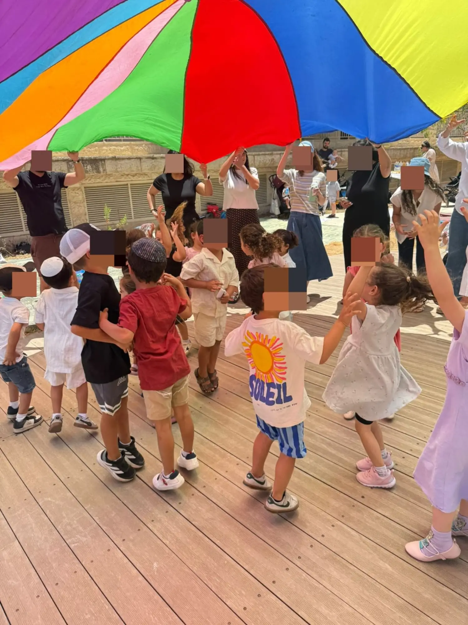 ילדים והורים משחקים במצנח צבעוני ענק במסיבת סיום בגן ירושלים